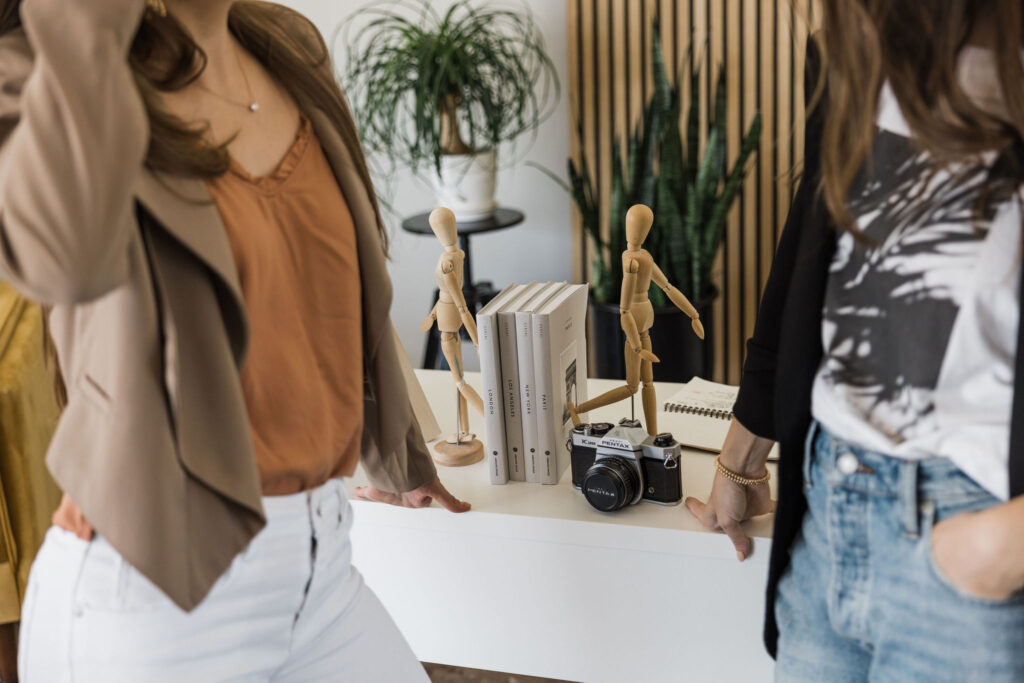 a woman standing next to a table with two wooden figurines